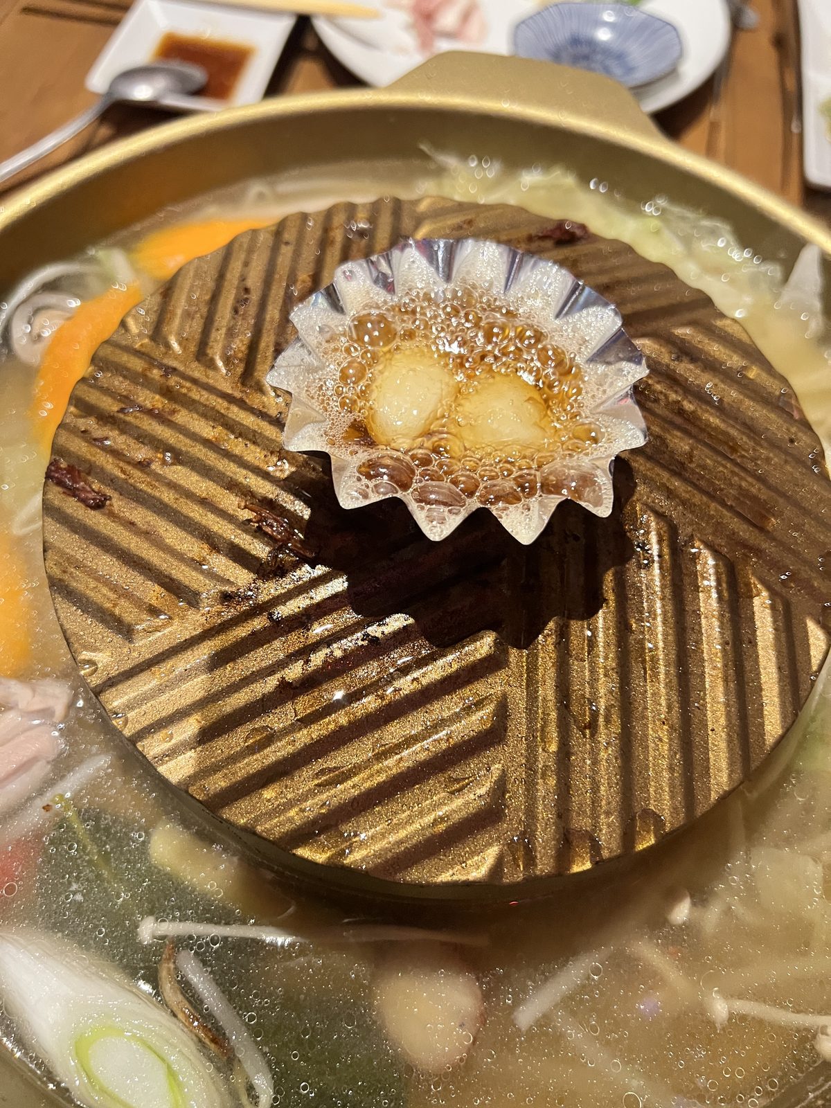 ムーガタ鍋の上でホイルカップに入れて焼く焼きニンニク