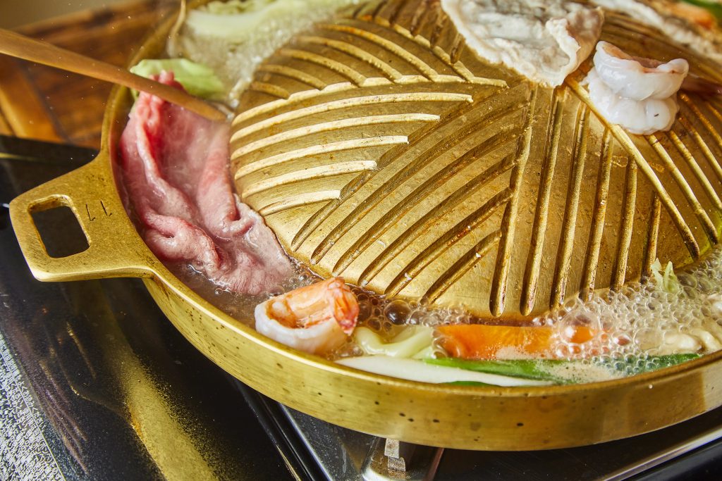 ムーガタのプレートでトングを使って豚肉を焼いているところ